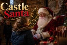 A family smiling at a Castle Santa sitting in a historic stone room beautifully decorated for Christmas.