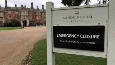 Close-up of an official Sandringham Estate emergency closure sign with the red brick main house in the background.