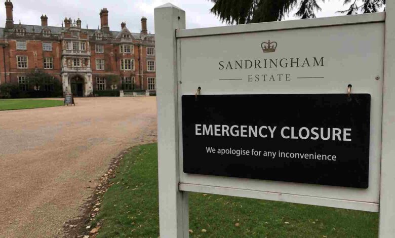 Close-up of an official Sandringham Estate emergency closure sign with the red brick main house in the background.