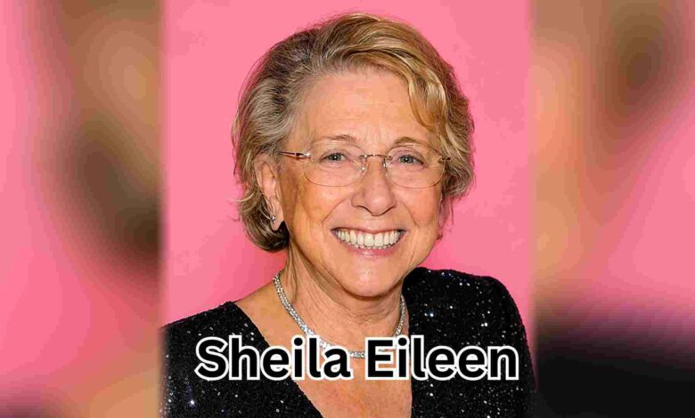 A color portrait of older Sheila Eileen smiling in a black sequined dress against a pink background.